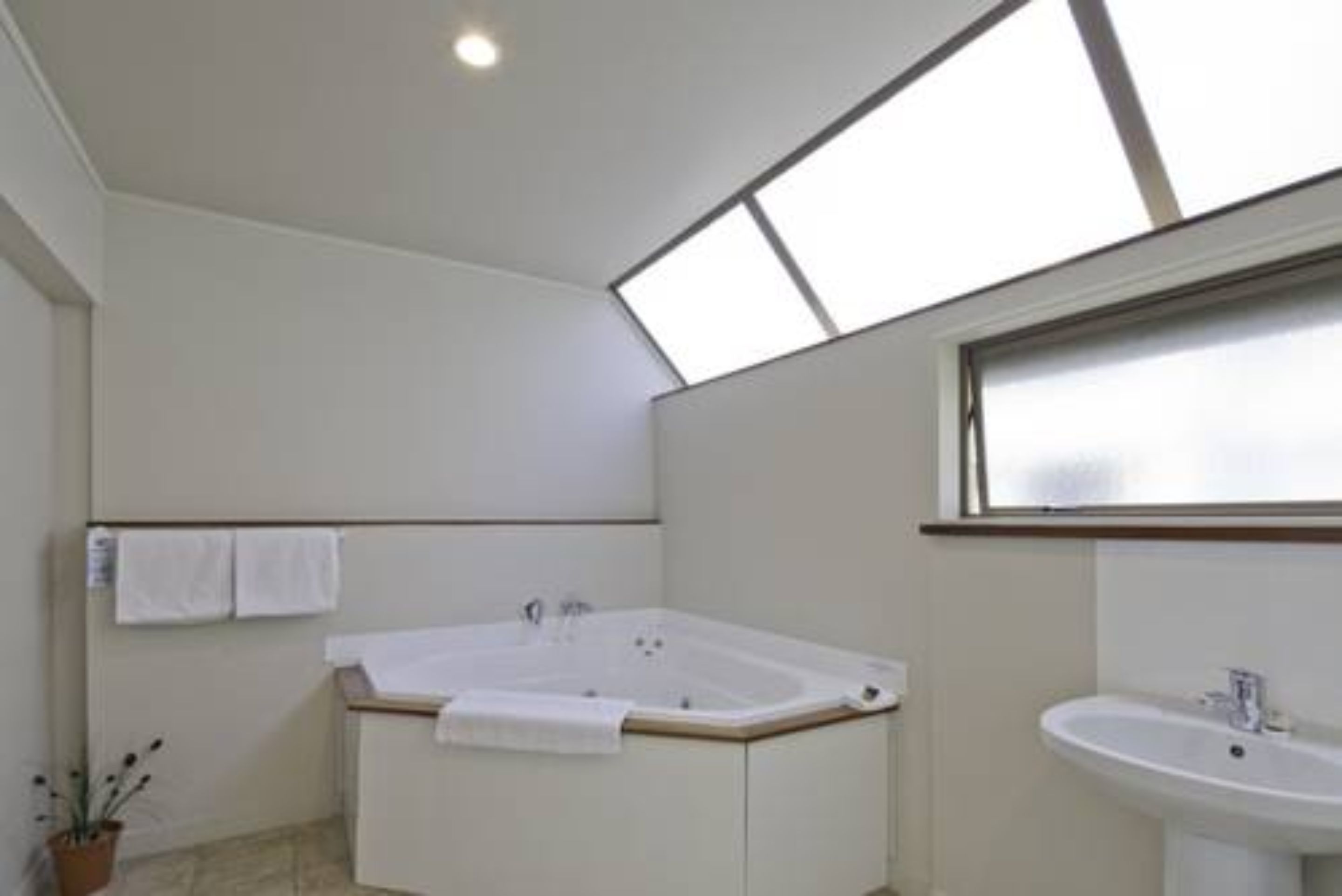A modern bathroom with a freestanding bathtub, a sink, and a skylight above.