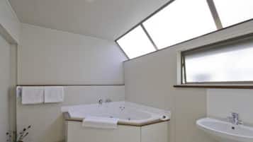 A modern bathroom with a freestanding bathtub, a sink, and a skylight above.