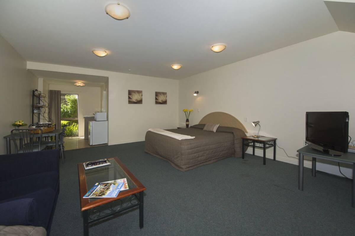A bedroom with a bed, a TV, a desk, and a chair.