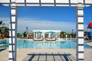 Ein Poolbereich mit blauem Himmel, Liegestühlen, Sonnenschirmen und einer Pavillon-Struktur.