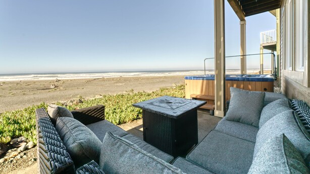 Eine Terrasse mit Blick auf den Strand, Gartenmöbel und einem Whirlpool.