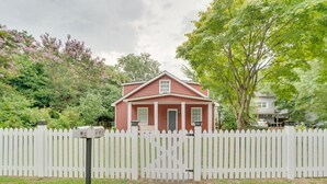Ett rött hus med ett vitt staket, en brevlåda och en gång som leder fram till ytterdörren.