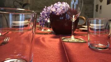 Ein Esstisch mit rotem Tischlein, klarem Glas und einer Vase mit violetten Blumen.