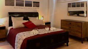 A neatly made bed with a red and white bedspread, a wooden nightstand with a lamp, and a wooden dresser with drawers. - Conti house, a cultural experience in the footsteps of Shakespeare (Padova)
