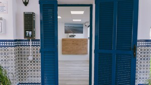 A reception area with a wooden desk, a framed picture on the wall, and a tiled floor.