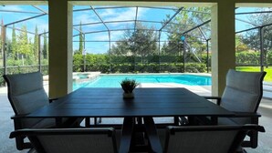 An outdoor dining area with a table and chairs, overlooking a swimming pool and a garden. - Beautiful 6 Bd Pool Spa Gm Solterra Resort-4396ac (Davenport)