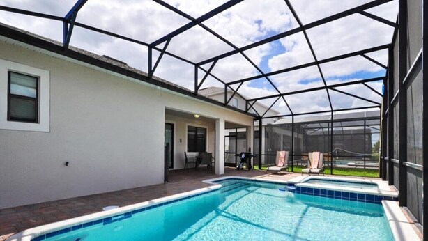 Une piscine intérieure dotée d’un toit en verre, entourée d’un bâtiment blanc avec un espace patio.