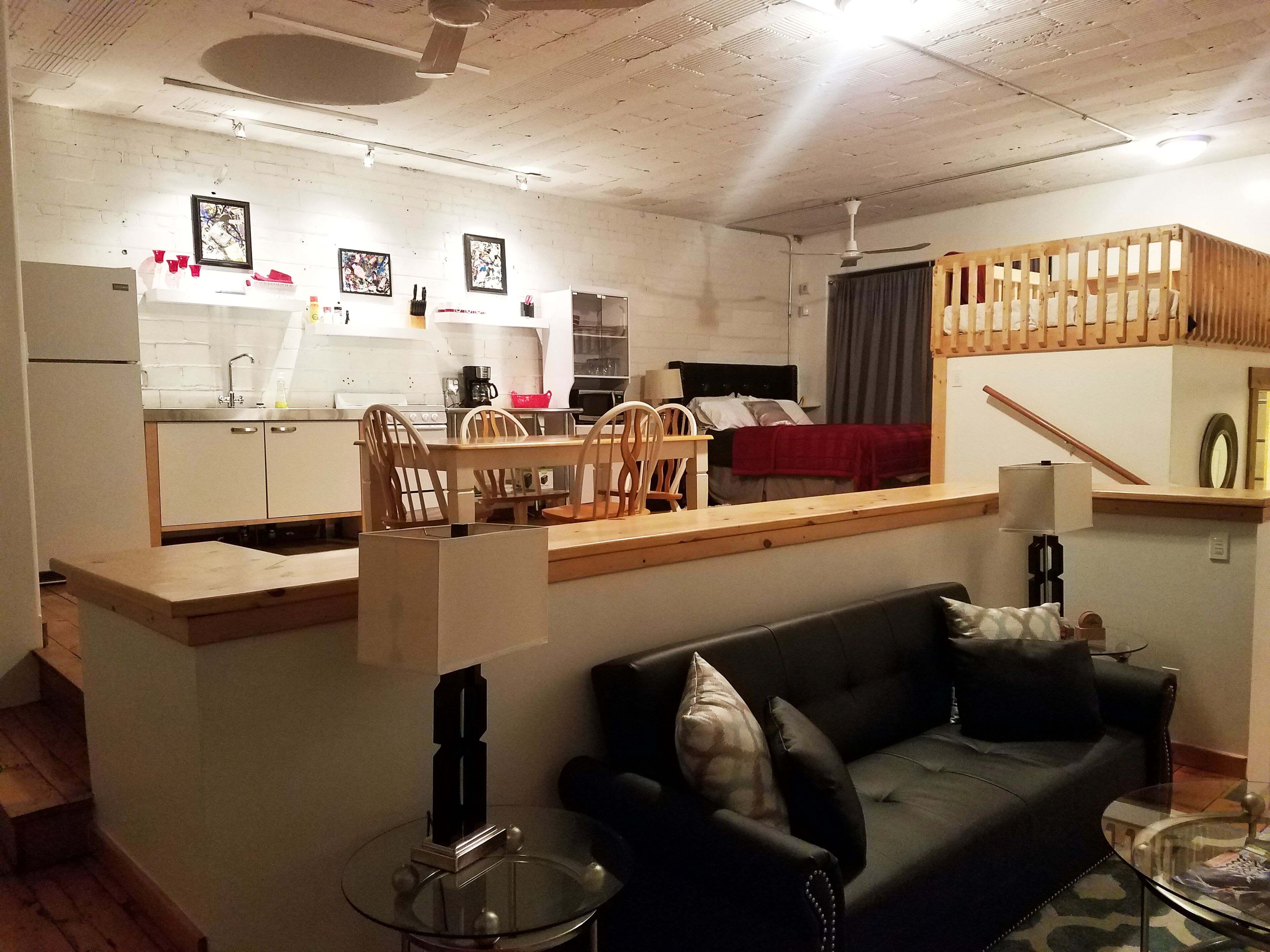 A compact living space with a kitchenette, a dining area, a sofa, and a staircase.