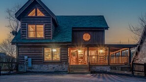 A log cabin with a porch, a garage, and a large front door.