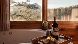 A wooden interior with a window view, a bottle of Edenbrook wine, a metal cup, and a tray with grapes.