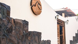 Un bâtiment doté d’un mur en pierre, d’une porte en bois et d’une enseigne circulaire représentant un motif de montagne.