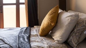 Une chambre à coucher avec un lit, une fenêtre avec des rideaux et un tableau accroché au mur.