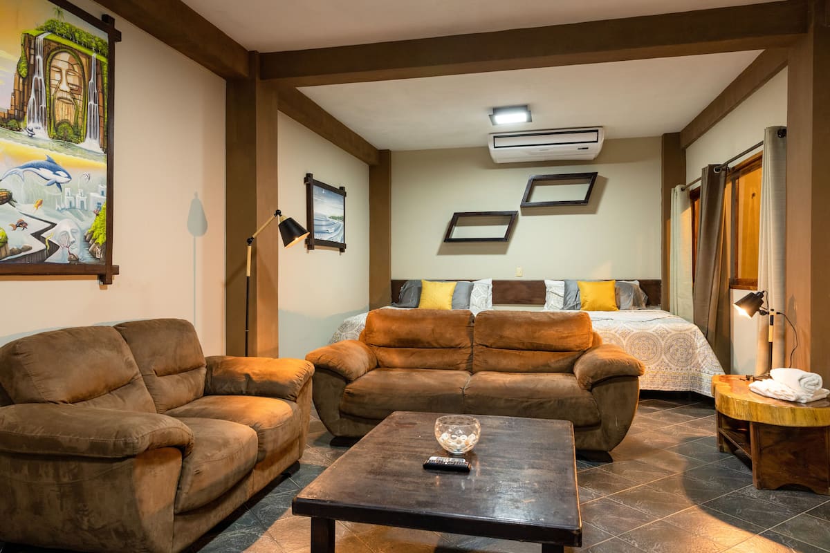 A cozy room with a bed, two sofas, a coffee table, and a painting on the wall.