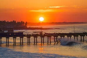 A pier extending into a body of water with a sunset in the background. - Ast Surf Hotel (La Libertad)