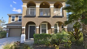A two-story house with a front porch, a garage, and a well-maintained garden with various plants. - Meticulous 6Bd Spa Gm Pool Hm Solterra-4187od (Davenport)