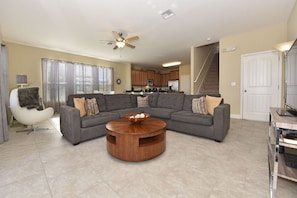 A living room with a sectional sofa, a wooden coffee table, and a modern chair. - Meticulous 6Bd Spa Gm Pool Hm Solterra-4187od (Davenport)