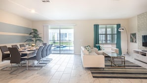 A modern living room with a dining area, a sofa set, a TV, and a large window with curtains.