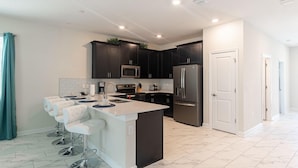A modern kitchen with dark cabinets, stainless steel appliances, and a central island with bar stools.