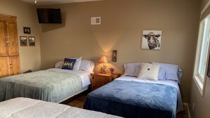 A bedroom with two beds, a wooden wardrobe, a TV, and wall art. - Attractive Country Get-a (Abbeville)