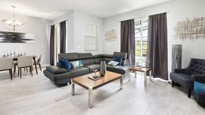 A modern living room with a sectional sofa, a coffee table, and a dining area with a table and chairs. - Champions Gate-8919ltsdjgilthp (Davenport)