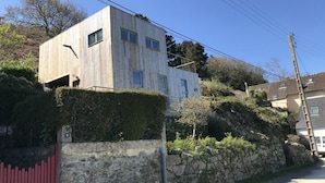 A modern two-story building with a stone wall and a red gate.