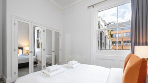 Una habitación de hotel con una cama grande, vistas de la ciudad a través de una ventana y un armario con espejo.