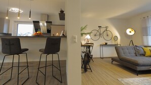 Una sala de estar moderna con un sofá, un comedor con sillas, una bicicleta y una cocina al fondo.