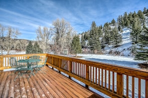 Enjoy the serene view from this deck, overlooking the snow-covered trees and surrounding landscape.