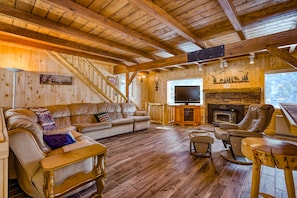Cozy living room with a stone fireplace, comfortable seating, and a flat-screen TV.