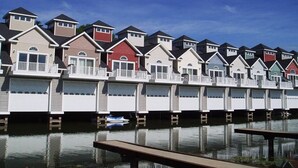 A row of waterfront houses with balconies, each with a garage door. - Waterfront Villa with Boathouse in Alexandria Bay (Alexandria Bay)