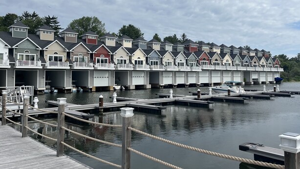 A row of waterfront condominiums with individual garages and a dock with moored boats. - Waterfront Villa with Boathouse in Alexandria Bay (Alexandria Bay)