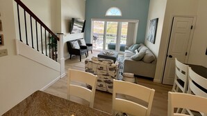 A spacious living area with a high ceiling, a ceiling fan, a large window, and a sliding glass door leading to an outdoor patio. - Waterfront Villa with Boathouse in Alexandria Bay (Alexandria Bay)
