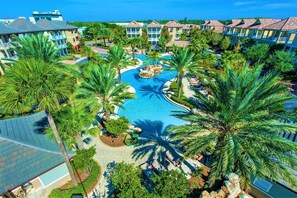 A resort with a central swimming pool, palm trees, and multiple-story buildings.