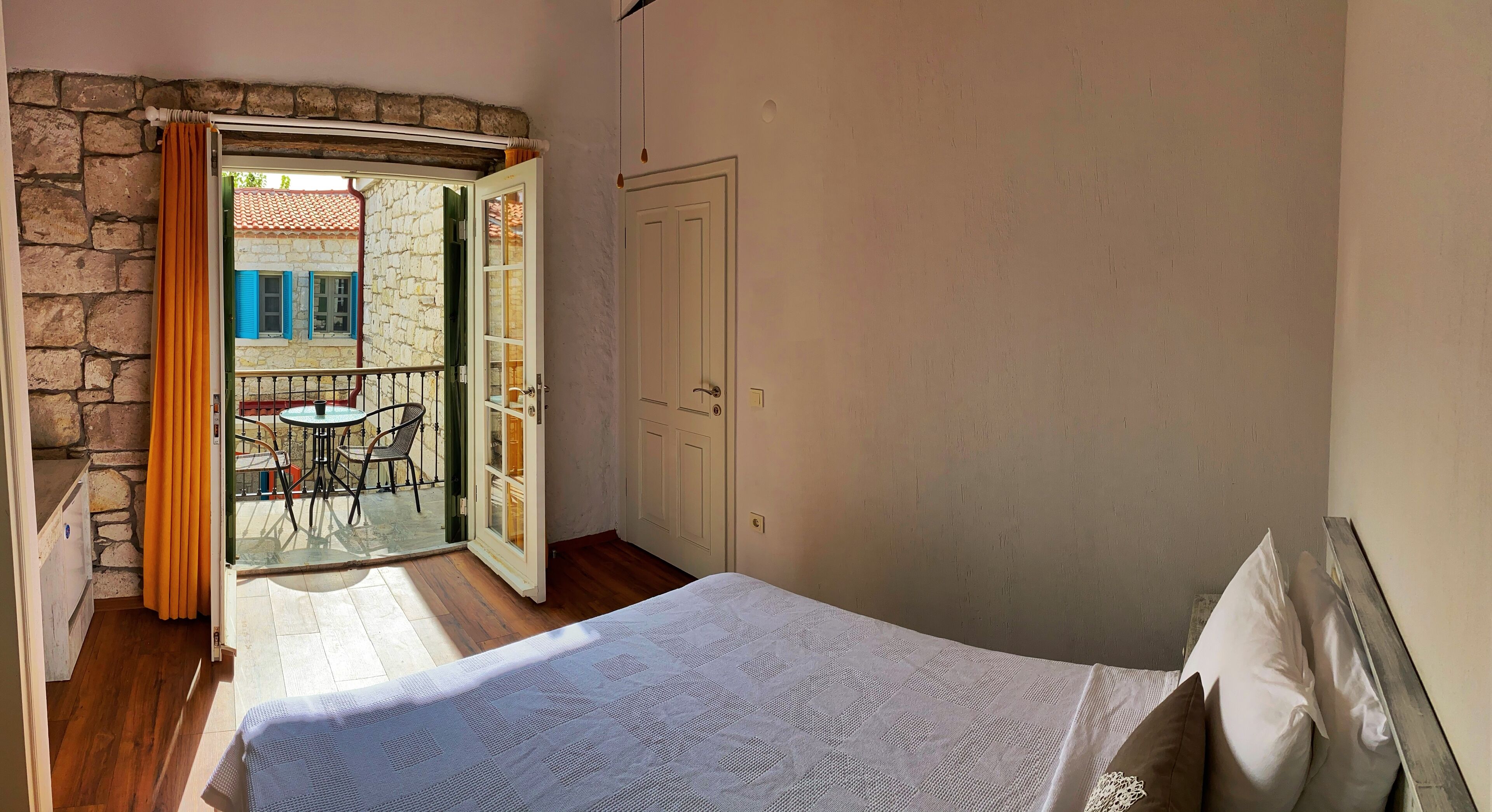 A bedroom with a bed, a door, and a view of an outdoor area with a table and chairs.