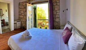 Ein Schlafzimmer mit einem großen Bett, einem Badezimmer und einem Balkon mit Steinmauer.