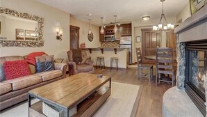A spacious living room with a fireplace, a dining area, and a kitchen. - 2 Bedroom Blackbear Lodge Condo in River Run Village (Keystone)