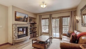 A living room with a stone fireplace, a leather sofa, and a coffee table. - 2 Bedroom Blackbear Lodge Condo in River Run Village (Keystone)