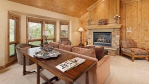 Un salon chaleureux avec une cheminée, un plafond en bois et de grandes fenêtres.