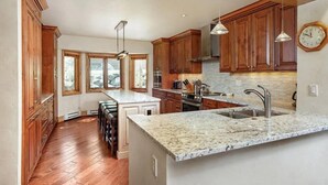 Une cuisine dotée de meubles en bois, de plans de travail en granit et d’un grand îlot central avec un évier.