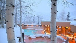 A snow-covered outdoor pool area with lounge chairs and a hot tub, surrounded by birch trees. - Snowmass Woodrun V 2 Bedroom Ski in, Ski out Mountain Residence in the Heart of Snowmass Village (Snowmass Village)