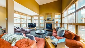 Un salon spacieux doté de grandes fenêtres, d’une cheminée et de sièges confortables.