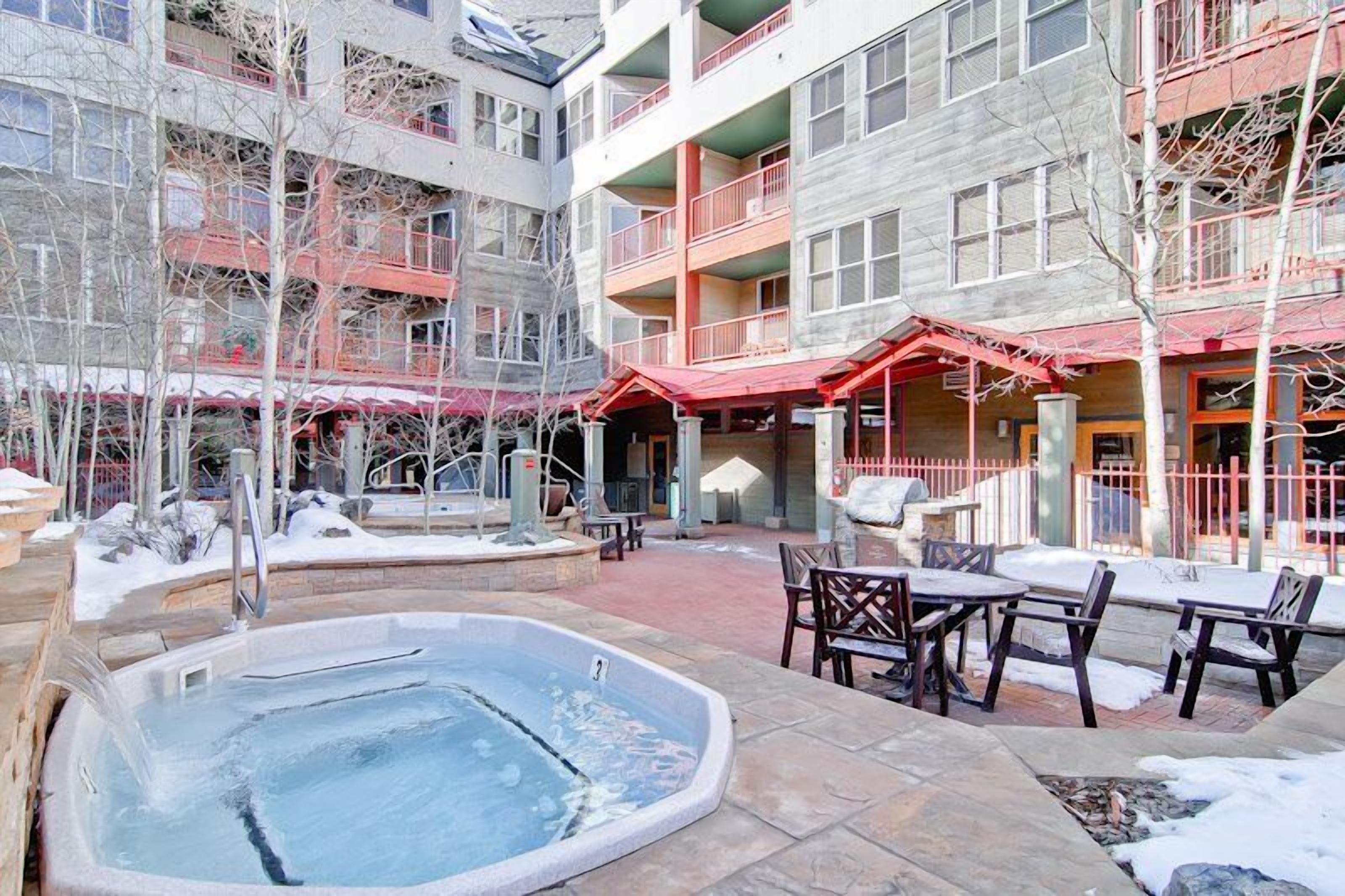 A multi-story building with outdoor seating and a hot tub.