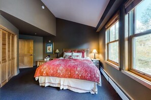 Ein Schlafzimmer mit einem großen Bett, einem Holzschrank und einem Fenster mit Blick.
