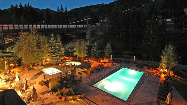 Un espace piscine doté d’un jacuzzi, de chaises longues et d’un pont en arrière-plan.