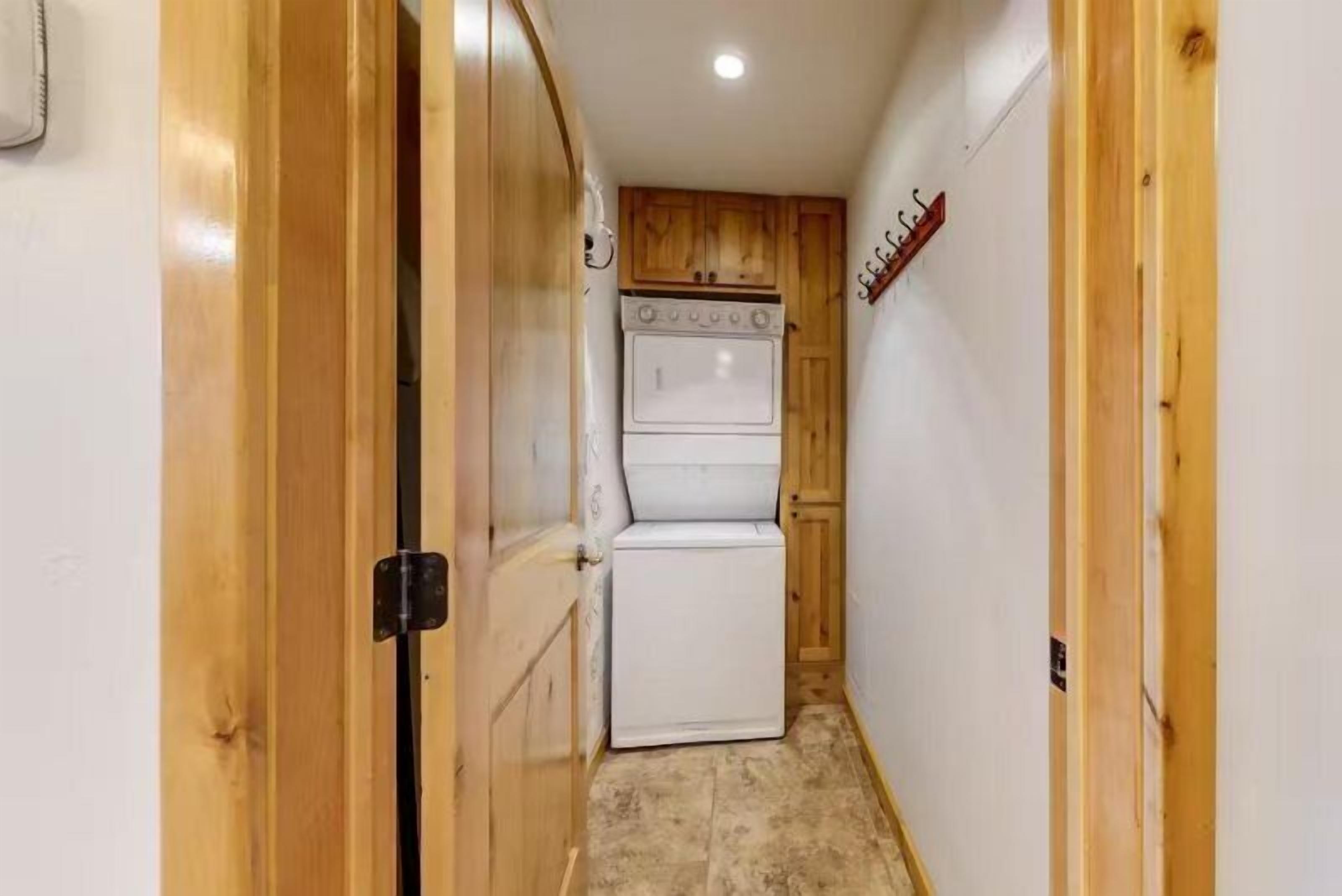 Un estrecho pasillo con puertas y paredes de madera, que conduce a una cocina con horno doble y refrigerador.