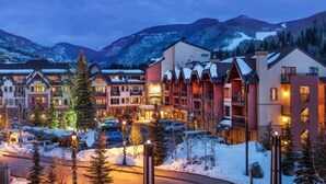 Un hôtel composé de plusieurs bâtiments, un parking et, en arrière-plan, des montagnes enneigées.