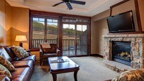 A living room with a fireplace, a sofa, a coffee table, and a television. - Ski in, Ski out 2 Bedroom Mountain Condo at the Base of Peak 7 with Quick Access to Historic Downtown Breckenridge (Breckenridge)