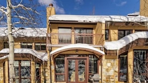 A two-story building with a stone facade and a balcony. - Snowmass Woodrun V 3 Bedroom Ski in, Ski out Mountain Residence in the Heart of Snowmass Village (Snowmass Village)