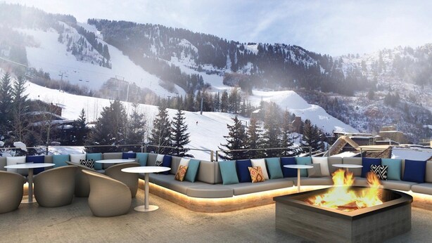 A cozy outdoor seating area with a fire pit, surrounded by sofas and round tables, overlooking a snowy mountain landscape. - Downtown Aspen Luxury 3 Bedroom Residence (Aspen)