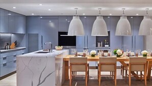 A modern kitchen with a marble island, pendant lighting, and a dining area set for six. - Downtown Aspen Luxury 3 Bedroom Residence (Aspen)